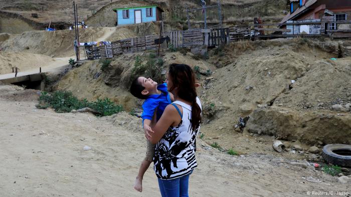 Mamá migrante abrazando a su hijo. 