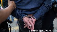 Symbolbild China Verdächtiger in Handschellen