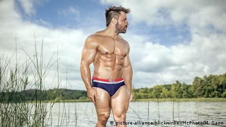  Muskulöser Mann in Badehose steht in einem See, (picture-alliance/blickwinkel/McPhoto/M. Gann)