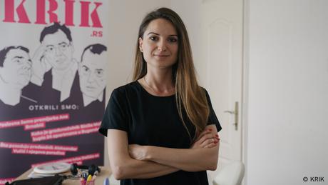 Dragana Peco in front of a poster showing the URL krik.rs