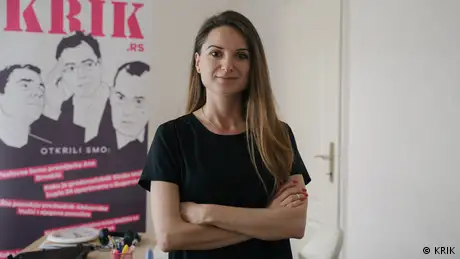 Dragana Peco in front of a poster showing the URL krik.rs