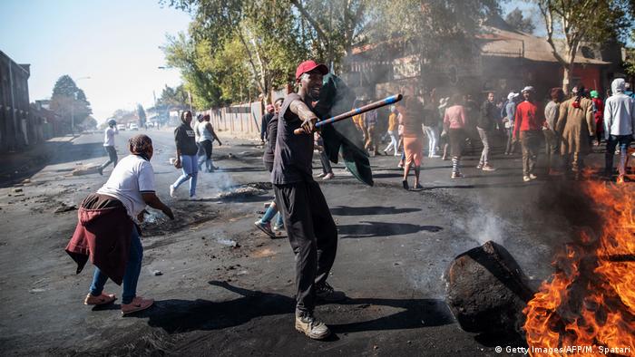 Rioters stand by burning debris in unrest aimed at migrants in Johannesburg