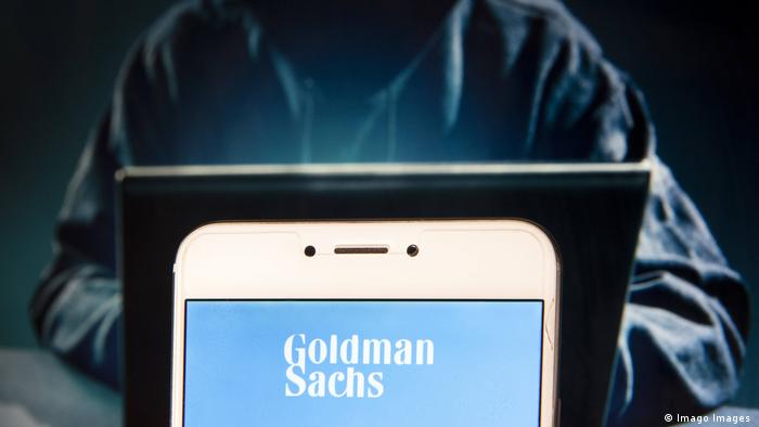A Goldman Sachs logo can be seen on a phone screen. 