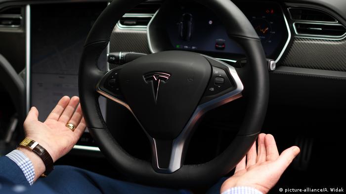 Čovjek u automobilu Tesla s rukama pored volana
