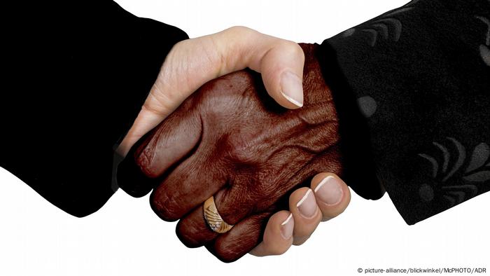 Duas mãos dadas, sendo uma negra e a outra, branca