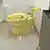 El retrete de oro brillante en un pequeño cuarto de baño