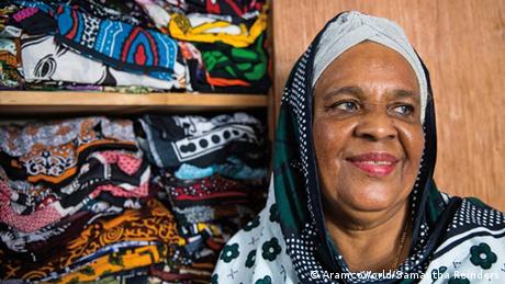 A woman next to a shelf of kangas (AramcoWorld/Samantha Reinders)