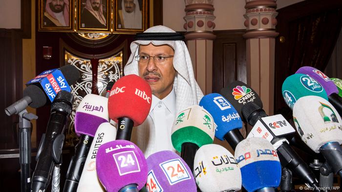 a man wearing a head scarf stands behind a row of microphones a man wearing a head scarf stands behind a row of microphones