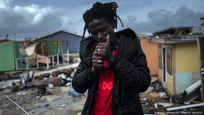 Man lights a cigarette next to the rubble of his home after Hurricane Dorian struck the Bahamas