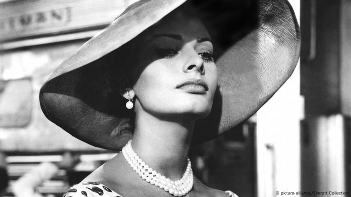 Sophia Loren trägt einen riesigen Hut und eine Perlenkette 