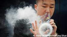 28.06.2019 A promoter of an e-cigarette company smokes an electronic cigarette at the Beijing International Consumer Electronics Expo on June 28, 2019. (Photo by WANG ZHAO / AFP) (Photo credit should read WANG ZHAO/AFP/Getty Images)