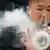 Ein Mann raucht E-Zigarette und bläst dabei Rauch aus der Nase, vor ihm schwebt ein Rauchkreis (Photo by WANG ZHAO / AFP)
