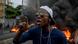 A man protesting in Haiti with a burning barricade in the background A man protesting in Haiti with a burning barricade in the background
