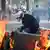 A French policeman tries to separate burning rubbish bins during protests in Paris