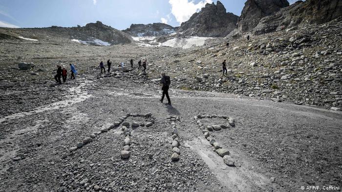 People take part in a ceremony to mark the 'death' of the Pizol glacier above Mels, in Switzerland. In this image, rocks have been used to mark out RIP