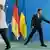 Angela Merkel walks away from Zelenskiy as he reaches towards a podium