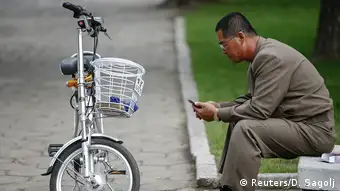 Nordkorea Mann mit Handy und E-Bike in Pyongyang