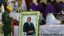 Soldiers stand beside a picture of former Zimbabwean President Robert Mugabe during a church service before his burial at his rural village in Kutama, Zimbabwe, September 28, 2019. REUTERS/Philimon Bulawayo