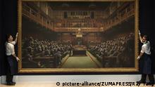 September 27, 2019, London, London, UK: London, UK. Sotheby's staff hold a painting titled Devolved Parliament, 2009, by artist Banksy. The painting depicts MP's in the houses of Parliament with an estimate of ÃÂ£1.5-2 million. The work is part of the Sotheby's contemporary art auction. (Credit Image: Â© Ray Tang/London News Pictures via ZUMA Wire |
