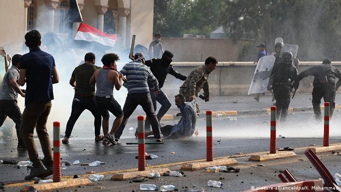 Security forces run after protesters in Baghdad while unleashing tear gas (picture-alliance/dpa/K. Mohammed)