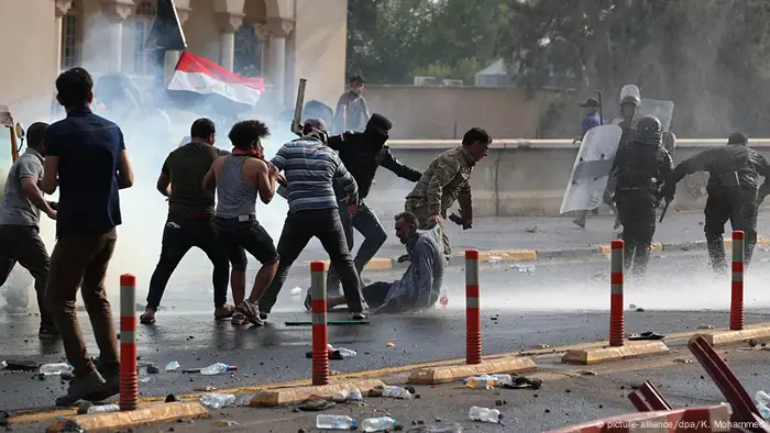Security forces run after protesters in Baghdad while unleashing tear gas (picture-alliance/dpa/K. Mohammed)