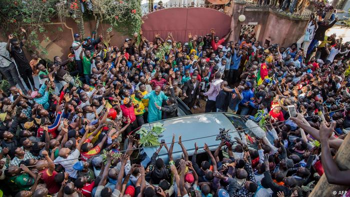 People surrounding car with Maurice Kamto in it