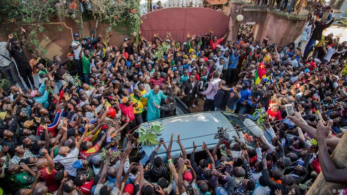 People surrounding car with Maurice Kamto in it