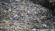 TOPSHOT - This photo taken on May 30, 2018 shows a rag picker walking along a sewage drain canal full of garbage in the Taimur Nagar slum area in New Delhi. - A sea of plastic spreads through the New Delhi slum of Taimur Nagar, a symbol of the grime and waste that makes the Indian capital one of the world's most polluted cities. India is to be the focus of World Environment Day on June 5, but it is far from the minds of the long-suffering inhabitants of Taimur Nagar. (Photo by Dominique FAGET / AFP) / TO GO WITH India-health-environment-pollution by Abhaya Srivastava (Photo credit should read DOMINIQUE FAGET/AFP/Getty Images)