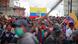 Manifestantes fazem passeata na rua, com bandeira do Equador Manifestantes fazem passeata na rua, com bandeira do Equador