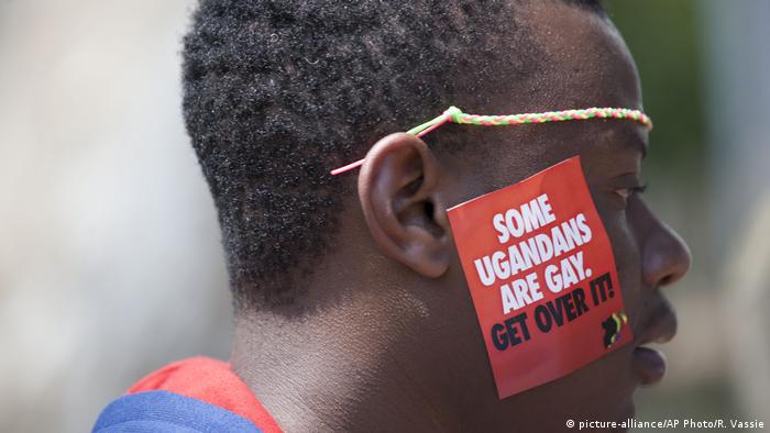 Image of a man with a sticker reading some Ugandans are gay, get over it at a gay pride parade in Uganda in 2014