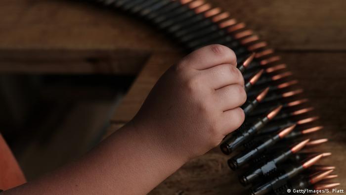 Foto simbólica de una mano infantil sobre munición