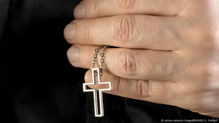 Religion l Hand hält eine Kette mit Kreuzanhänger