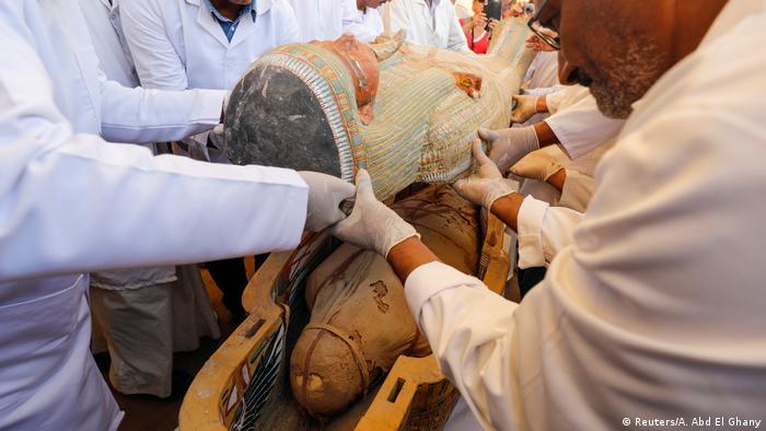 Archaeologists remove the cover of an ancient painted coffin discovered at al-Asasif Necropolis in the Valley of King