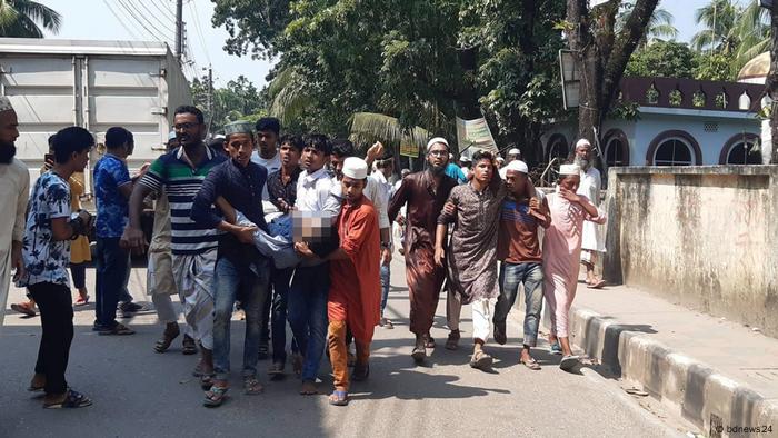 People in Bangladesh carry an injured man on a stretcher following violent clashes with police