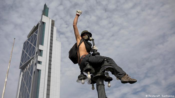 Un hombre subido a un farol en protestas en Santiago de Chile.