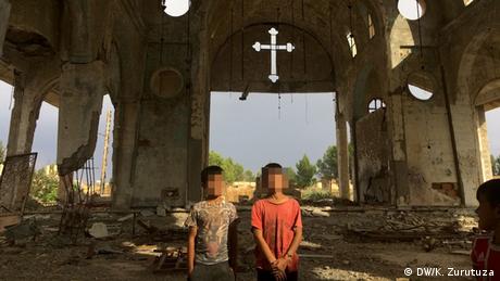 Two boys stand in a destroyed church