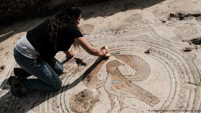 Eine Frau kniert auf einem Mosaik (picture-alliance/ZUMAPRESS.com/N. Alon)