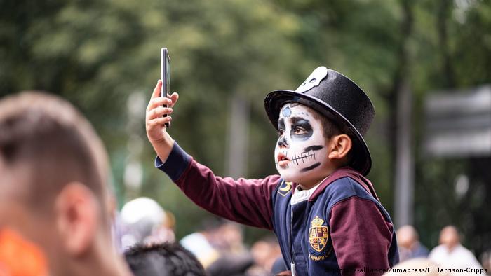 Un niño se toma un selfie disfrazado de calavera.