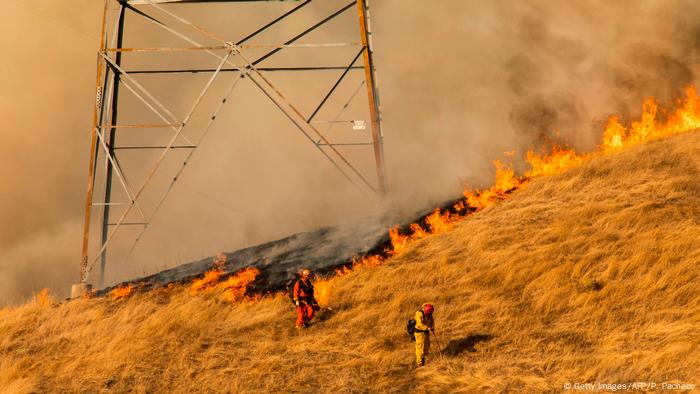 Feuerwehrleute kämpfen am Fuße einer PG&E-Stromtrasse gegen die Flammen