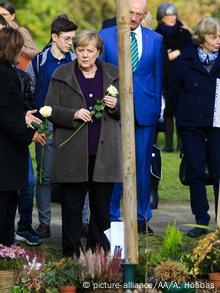 Η καγκελάριος Μέρκελ με ένα λευκό τραντάφυλλο στο μνημείο γα τα θύματα της NSU