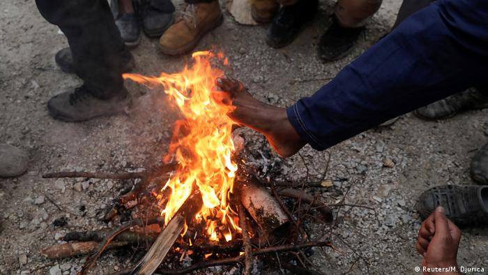 Migranti se griju pored vatre na otvorenome