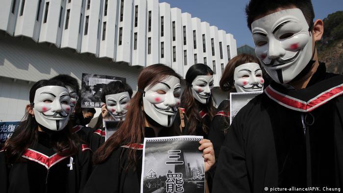 Maskierte Hongkonger Studenten singen bei ihrem Abschluss