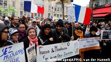 People wave French national flags, chant slogans and hold placards reading messages such as French and Muslim, proud of our both identities (C) and Don't touch my veil, respect my choice, no to Islamophobia as they take part in a demonstration march in front of the Gare du Nord, in Paris to protest against Islamophobia, on November 10, 2019. (Photo by GEOFFROY VAN DER HASSELT / AFP) (Photo by GEOFFROY VAN DER HASSELT/AFP via Getty Images)