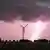 Ein Blitz schlägt in der Nähe eines Windrades ein, während eine Unwetterfront über die Region hinwegzieht