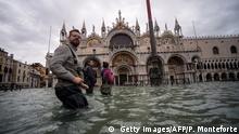 A general view shows people walking across the flooded St. Mark's Square, by St. Mark's Basilica on November 15, 2019 in Venice, two days after the city suffered its highest tide in 50 years. - Flood-hit Venice was bracing for another exceptional high tide on November 15, as Italy declared a state of emergency for the UNESCO city where perilous deluges have caused millions of euros worth of damage. (Photo by Filippo MONTEFORTE / AFP) (Photo by FILIPPO MONTEFORTE/AFP via Getty Images)