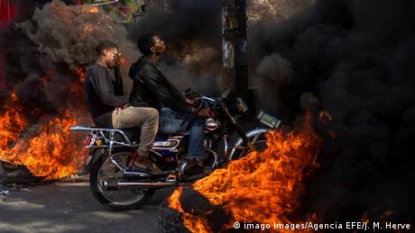 A motorcycle rides through black smoke from burning tires during a protest in Port-au-Prince in November 2019 (imago images/Agencia EFE/J. M. Herve)