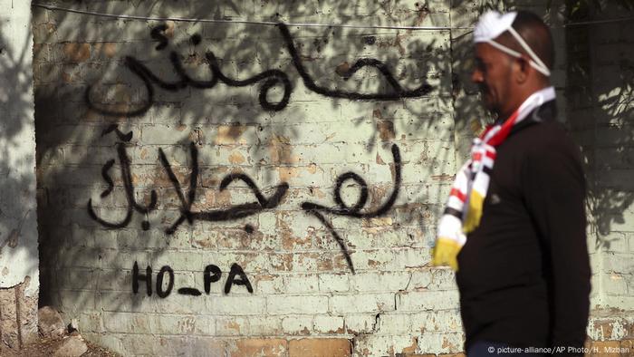 Irak Bagdad Protestierender vor Schriftzug (picture-alliance/AP Photo/H. Mizban)
