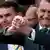 Presidente Jair Bolsonaro sorri e junta as mãos ao lado de seu filho Flávio Bolsonaro