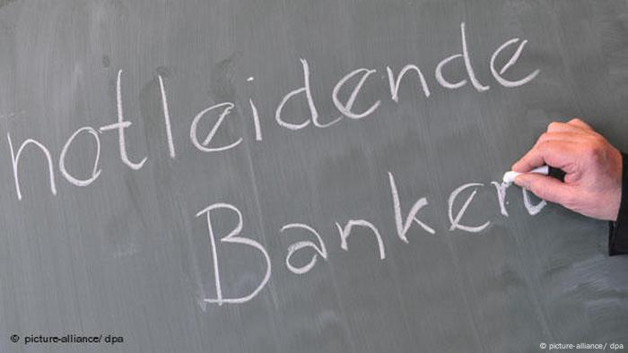 Jemand schreibt mit Kreide notleidende Banken auf eine Tafel (picture-alliance/ dpa)