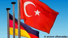 Türkische und deutsche Nationalflaggen wehen vor blauem Himmel. | Verwendung weltweit